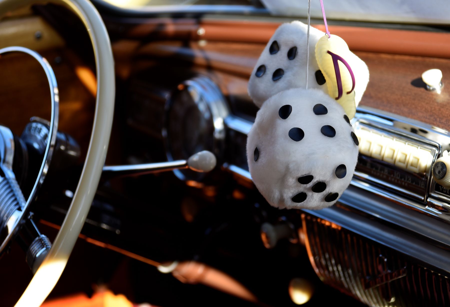 A pair of fuzzy dice hanging from a rearview mirror in the cabin of a classic car on display in Santa Fe, New Mexico