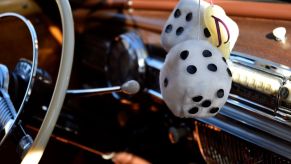 A pair of fuzzy dice hanging from a rearview mirror in the cabin of a classic car on display in Santa Fe, New Mexico