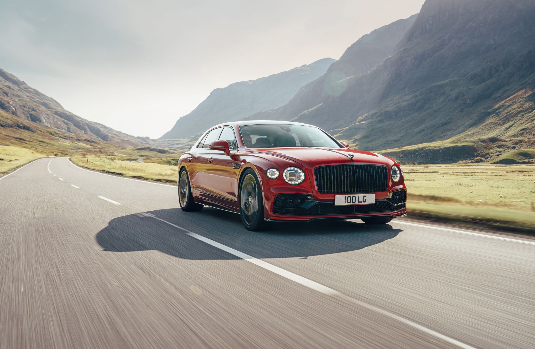 A red Bentley Flying Spur V8 high-performance luxury sports car driving on an open country highway