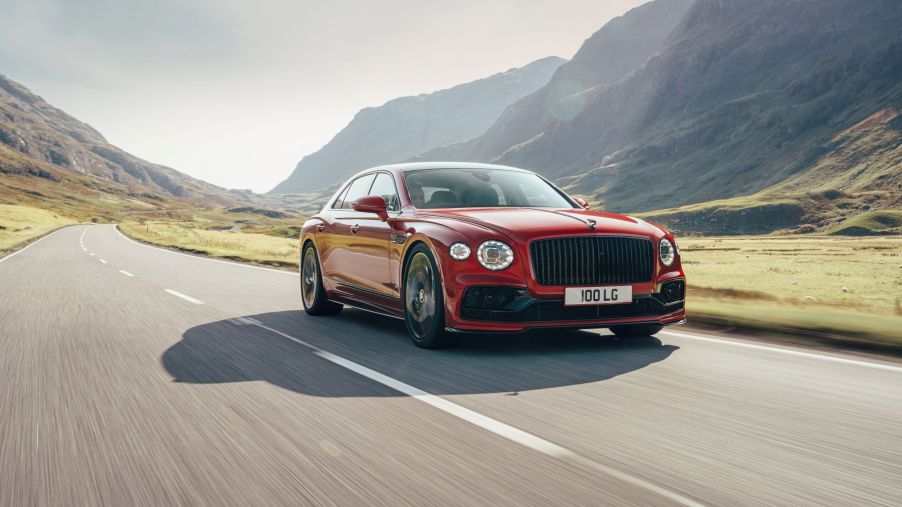 A red Bentley Flying Spur V8 high-performance luxury sports car driving on an open country highway