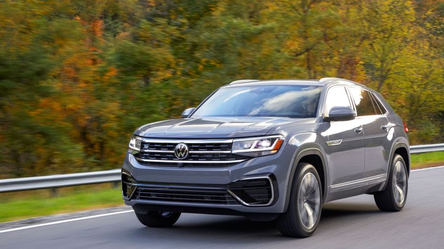 A gray 2022 Volkswagen Atlas Cross Sport premium two-row midsize SUV model driving on a forest highway road