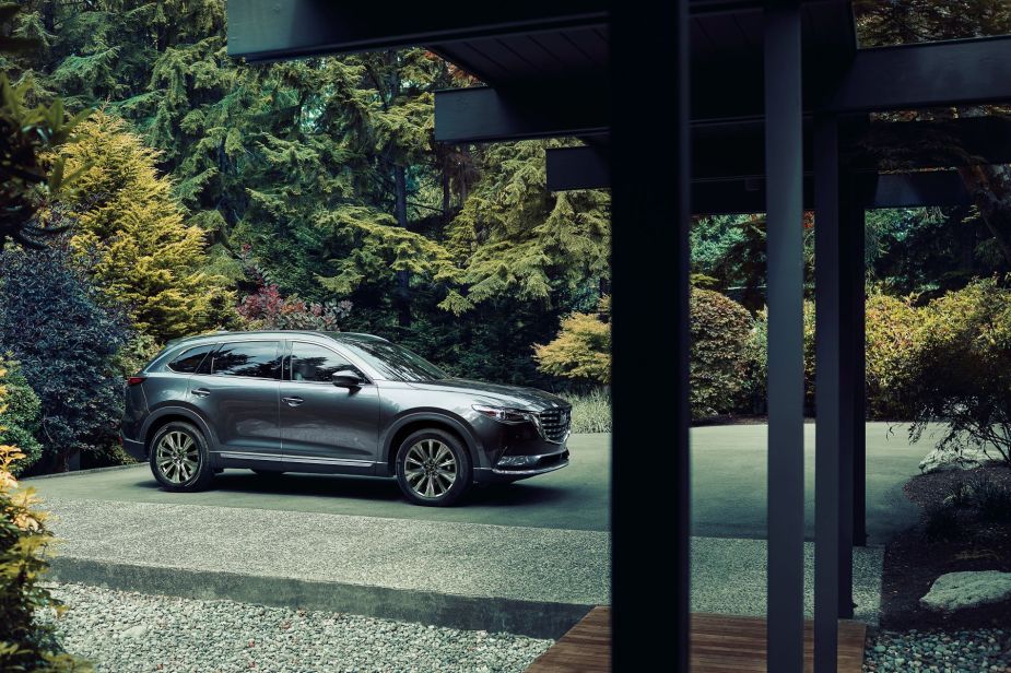 A steel gray Mazda CX-9 midsize SUV model parked outside of an excluded forest home