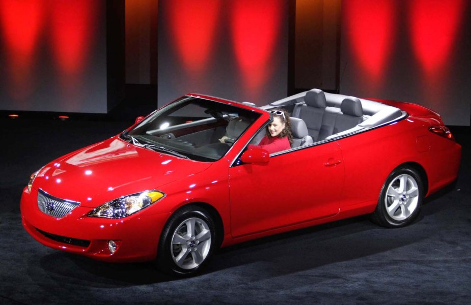 A reliable 2004 Toyota Camry Solara convertible finished in red and parked on the stage at an auto show.