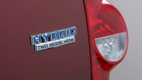 Closeup of a chrome "Hybrid Two Mode Hemi" badge on the rear of a red 2009 Dodge Durango full-size V8 SUV, one taillight visible as well.