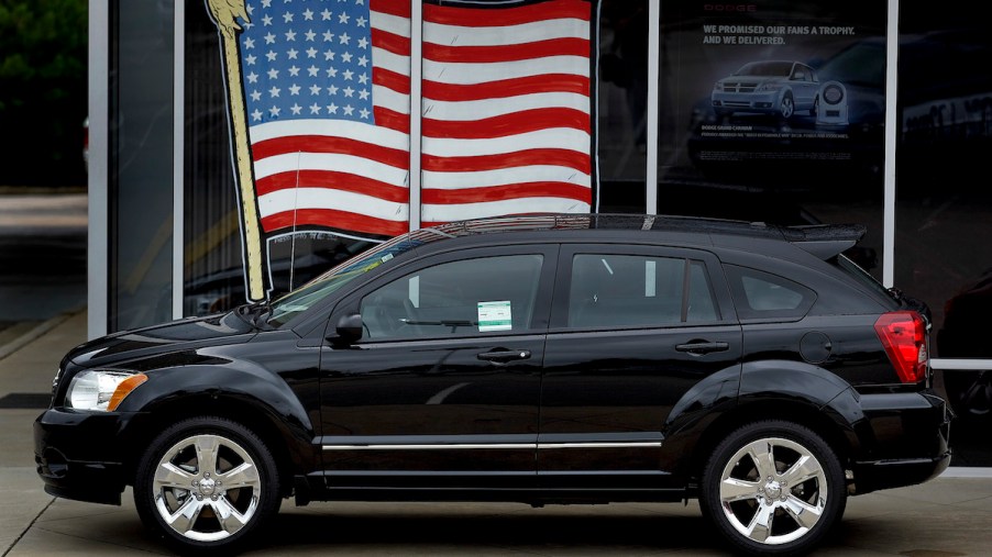 A black 2010 Dodge Journey parked in front of window with an American flag in the window.