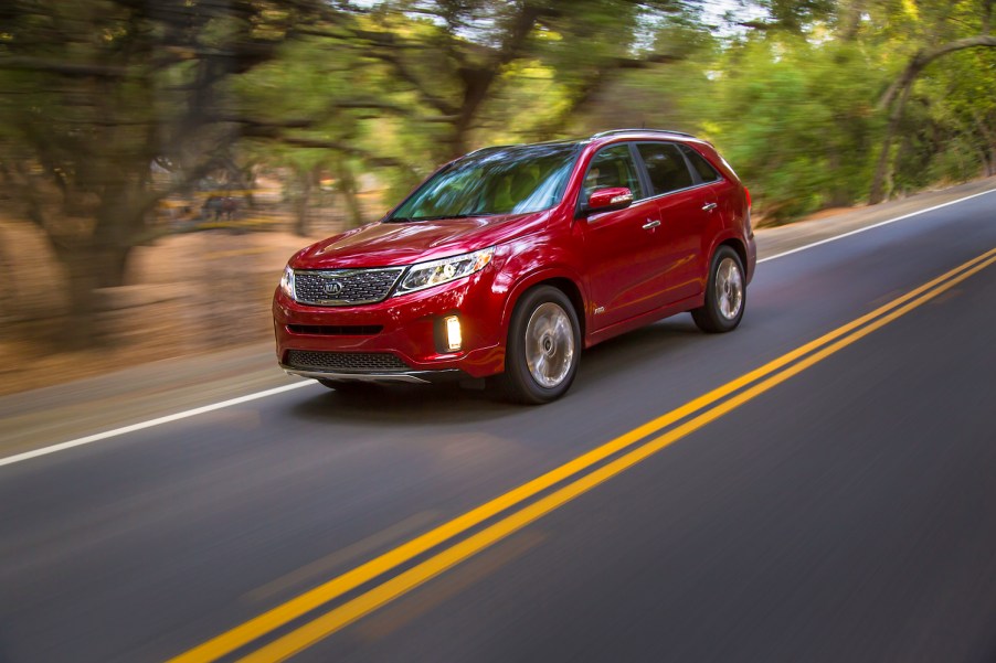 A red 2014 Kia Sorento used midsize SUV driving