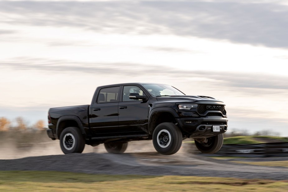 A black 2021 Ram 1500 TRX performance supercharged full-size pickup truck jumping off a dirt ramp
