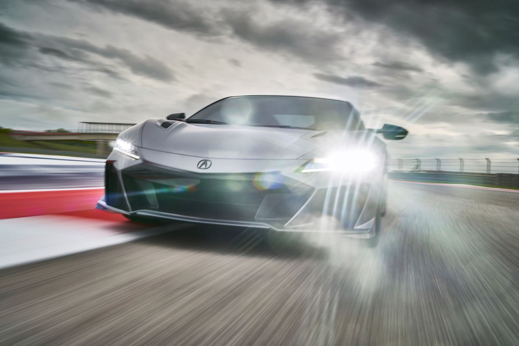 A gray 2022 Acura NSX Type S supercar driving on a racetrack under a stormy sky