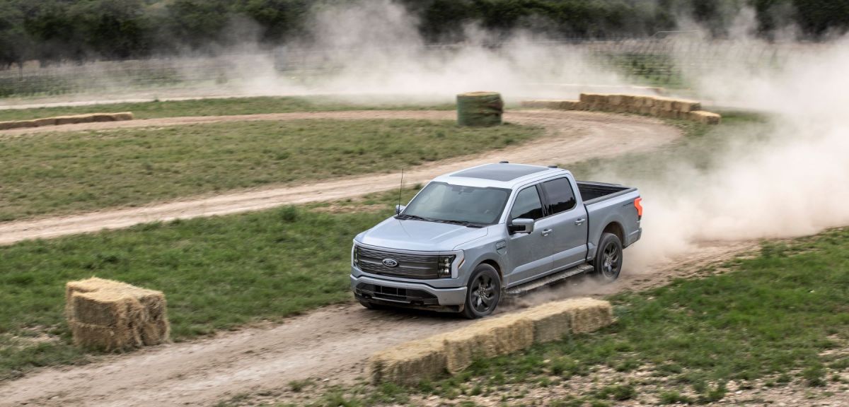 A gray 2022 Ford F-150 Lightning all-electric pickup truck model performing on a rally course