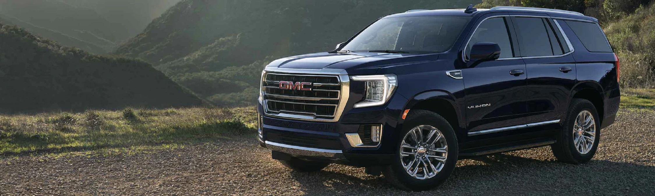 A dark blue 2022 GMC Yukon XL with a mountainous background.