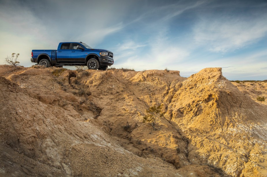 Blue Ram 2500 Power Wagon off-road truck parked atop a distant ridge line, the desert visible in the foreground.
