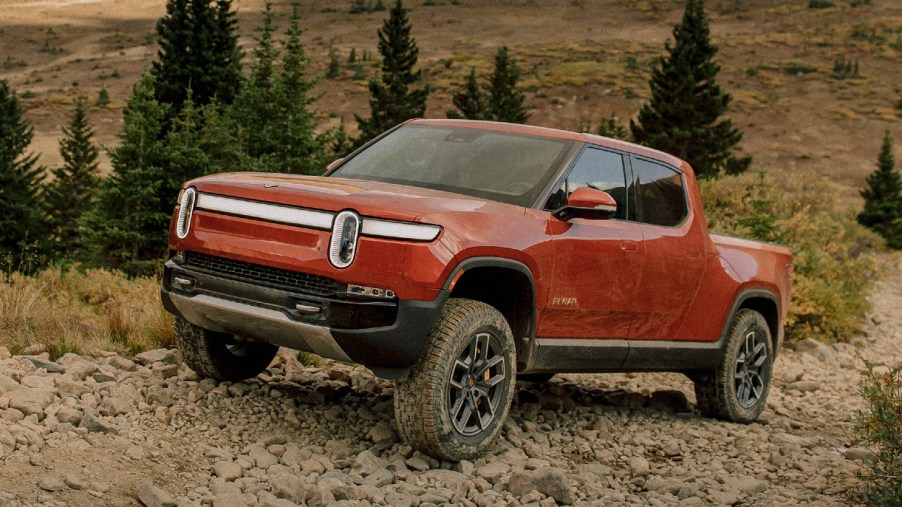 A red Rivian R1T electric truck is driving off-road.