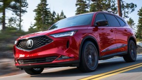 A red 2023 Acura MDX is driving on the road.