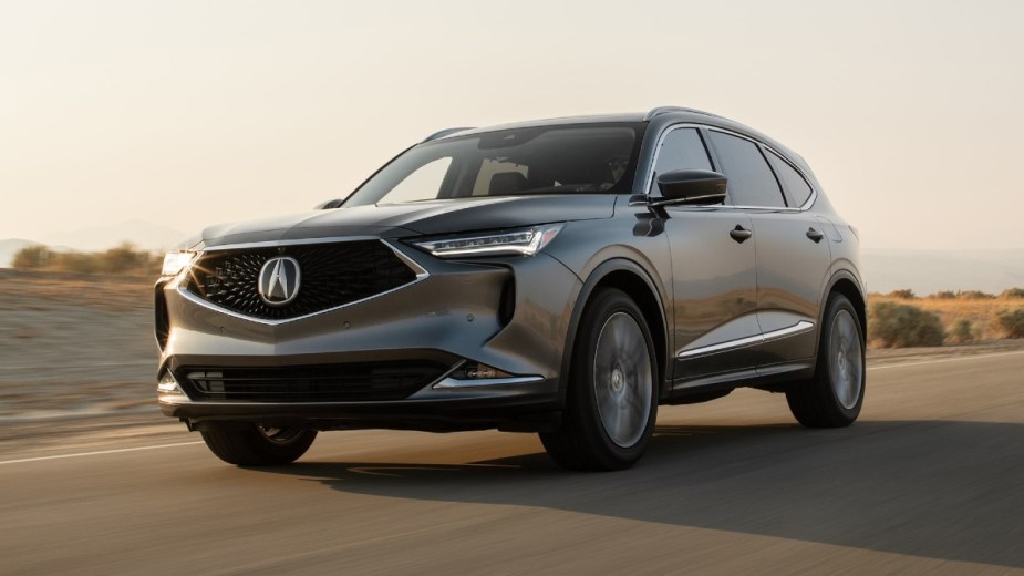 A gray 2023 Acura MDX is driving on the road. 