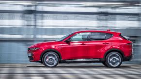 A side profile shot of a red 2023 Alfa Romeo Tonale plug-in hybrid electric vehicle (PHEV) SUV model with a blurred background