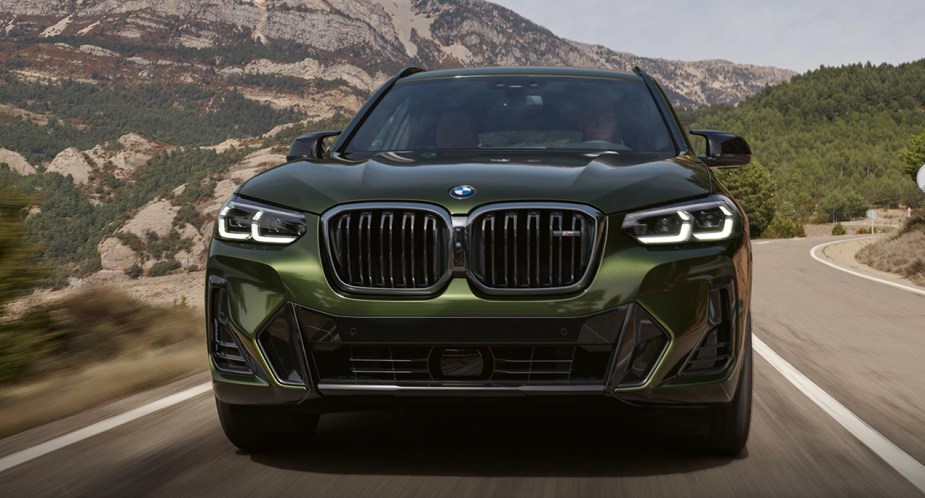 A green 2023 BMW X3 luxury small SUV is driving on the road. 