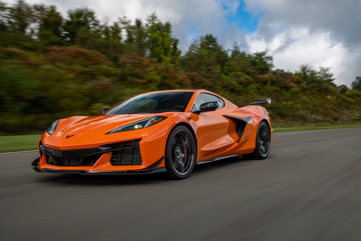 Side 3/4 view of 2023 Chevrolet Corvette Z06 in Amplify Orange Tint driving on a track.