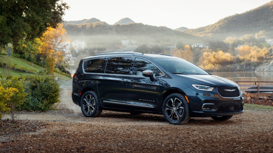 A dark 2023 Chrysler Pacifica PHEV parked in a fall scene.