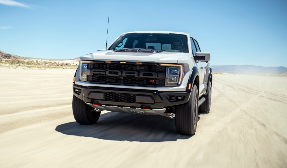 This is a promo photo of the F-150 Raptor R with its supercharged V8 in light gray, racing through the desert.