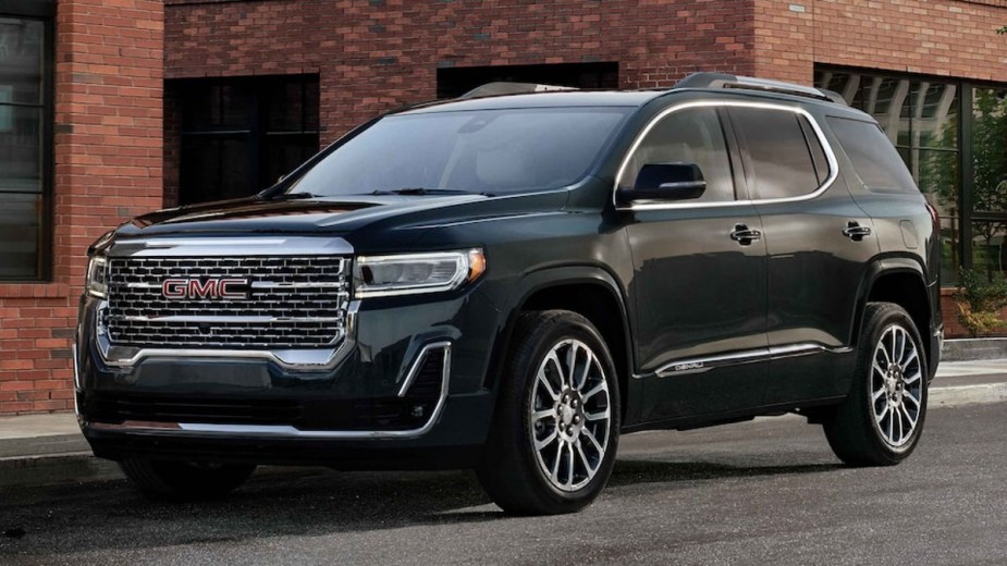 Black 2023 GMC Acadia Denali parked in front of a brick building
