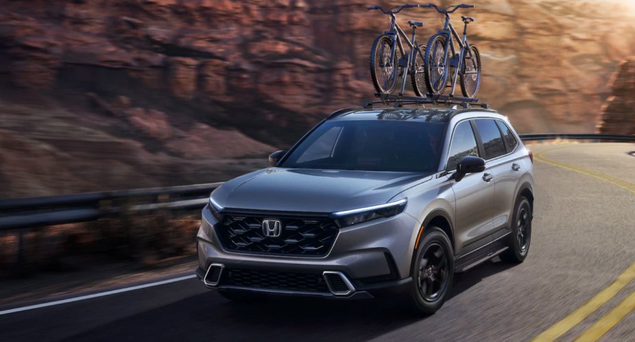 A gray 2023 Honda CR-V is driving on the road. 