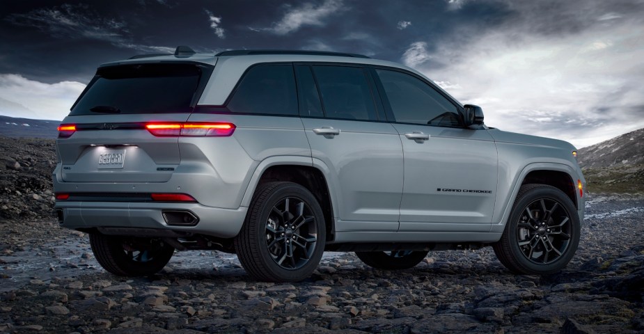 Promo photo of a silver Grand Cherokee 4xe plug-in hybrid SUV parked on a mountain top, a dark sky visible in the background.