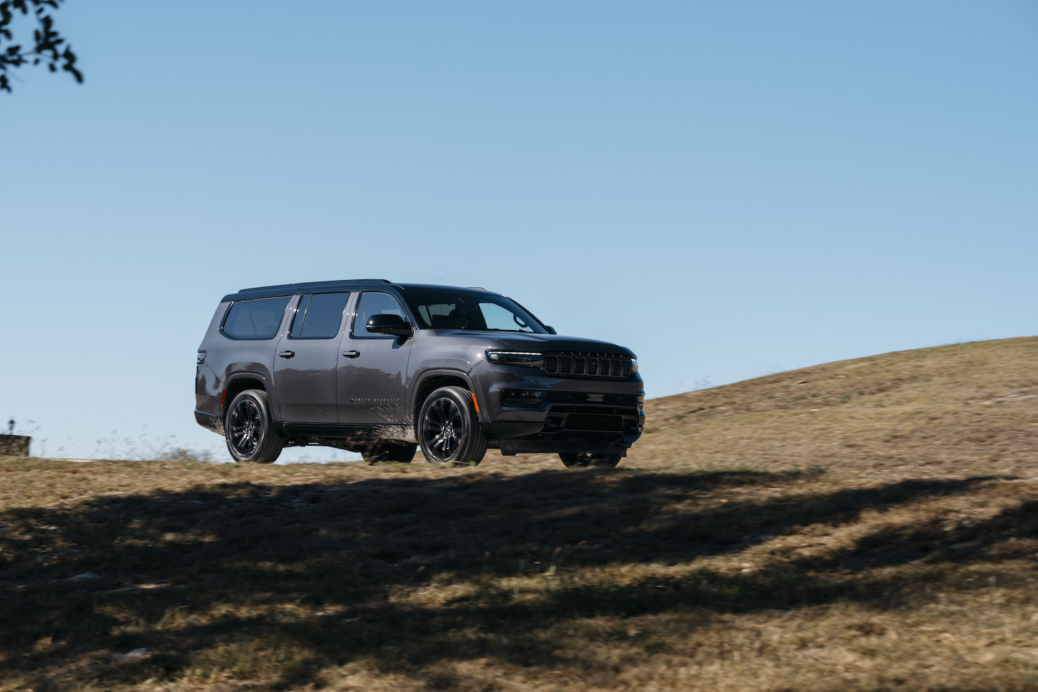 The 2023 Jeep Wagoneer blacked-out Carbide Edition with an I6 Hurricane Edition driving along a track, the blue sky visible in the background.