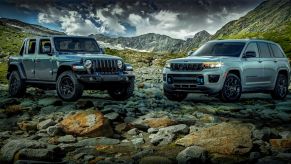 2023 Jeep Wrangler 4xe and 2023 Jeep Grand Cherokee 4xe models parked on a shore of rocks in the mountains