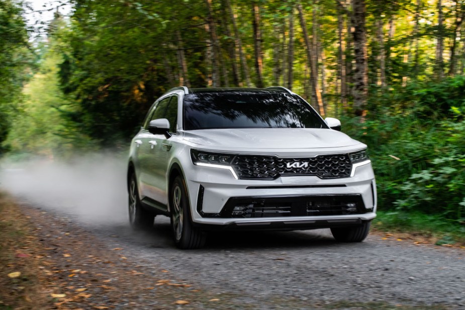 A 2023 Kia Sorento Hybrid driving down a dirt road in a wooded area.