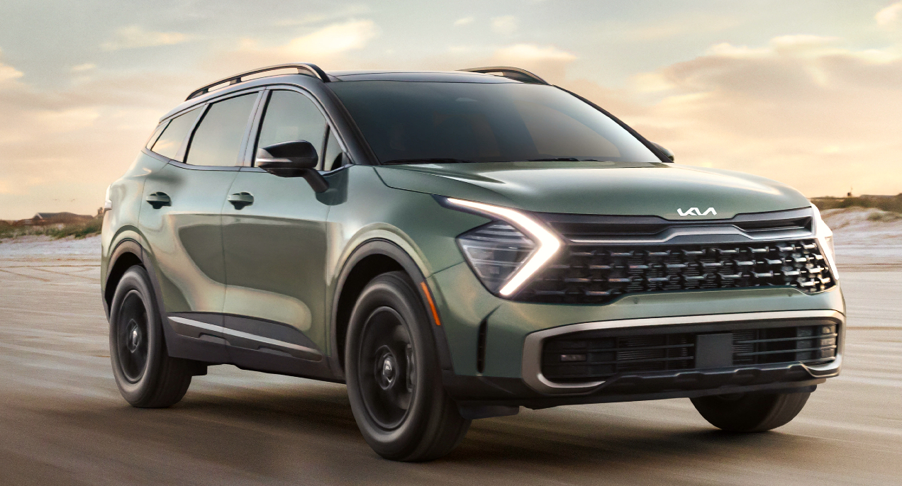 A green 2023 Kia Sportage small SUV is driving on the road.
