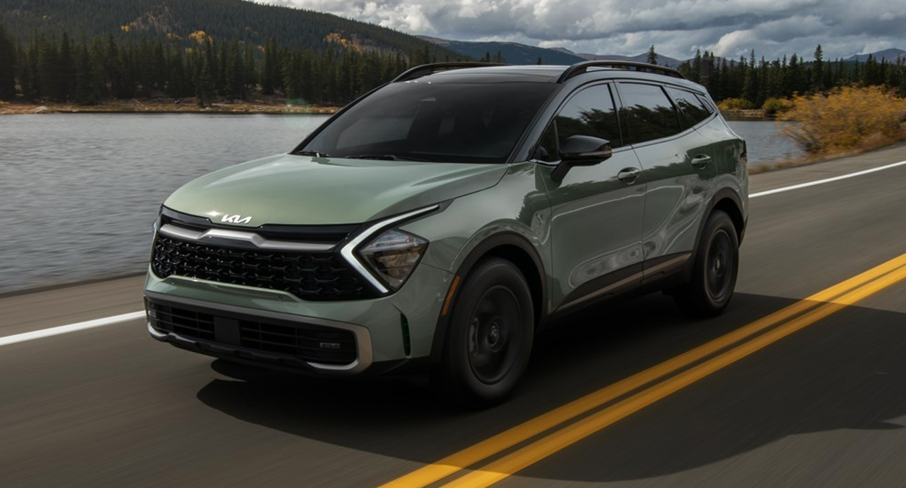 A green 2023 Kia Sportage small crossover is driving on the road.