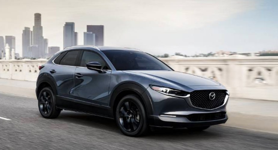 A gray 2023 Mazda CX-30 subcompact SUV is driving on the road.