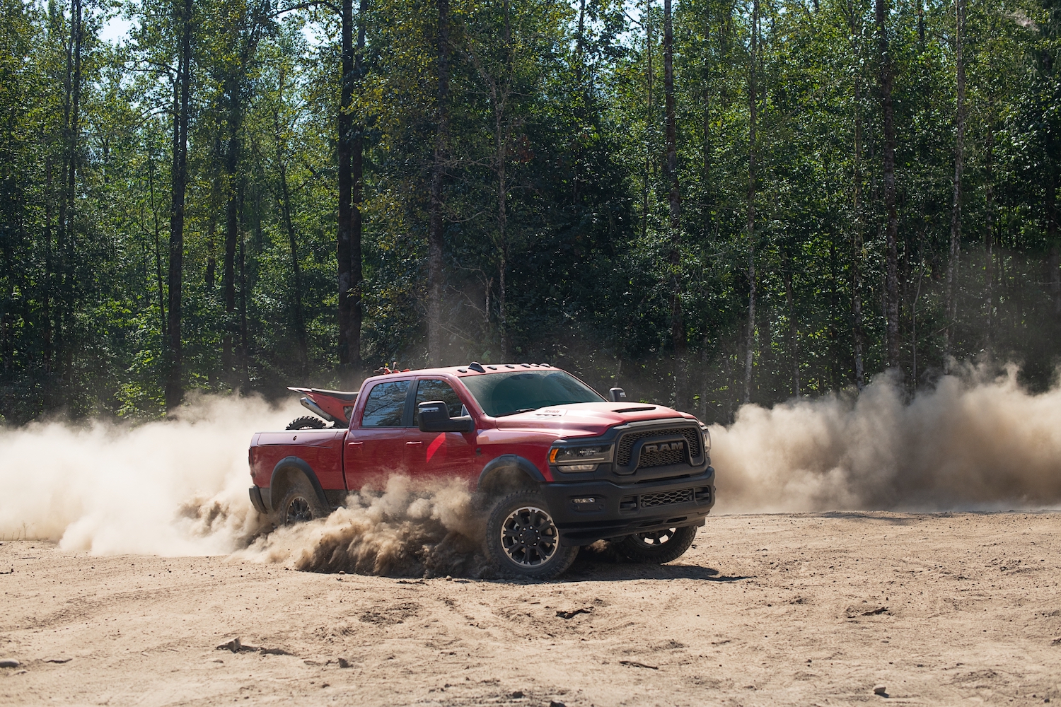 The Ram 2500 heavy-duty rebel truck drives off-road with a dirt bike in its pickup bed.