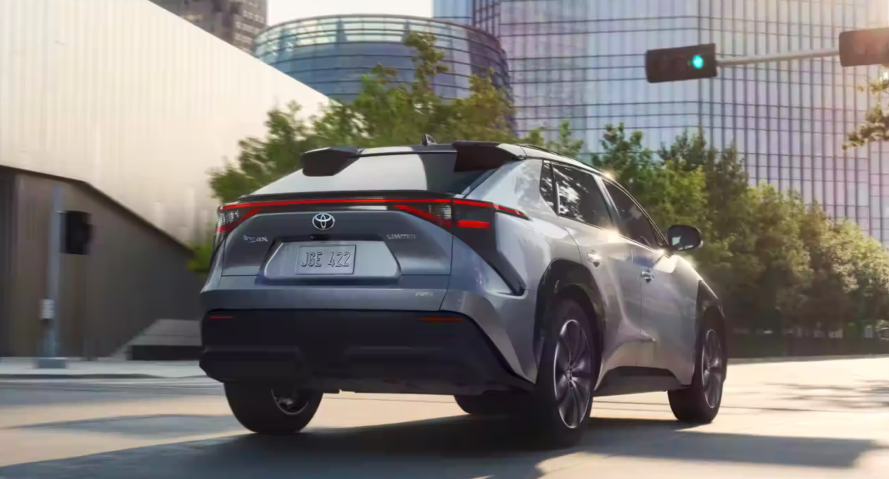 A gray 2023 Toyota bZ4X small electric SUV is driving on the road. 