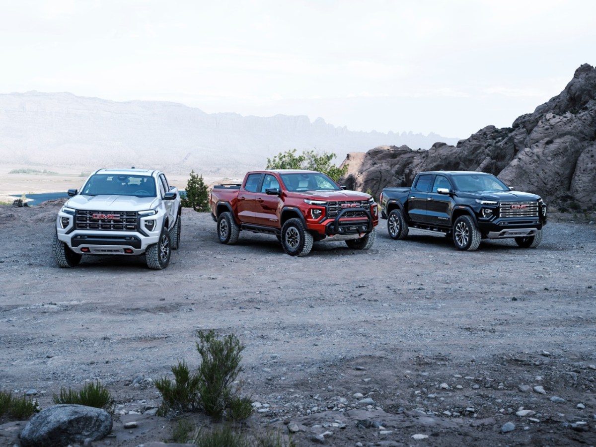 Three versions of the 2023 GMC Canyon parked on a dirt area. 