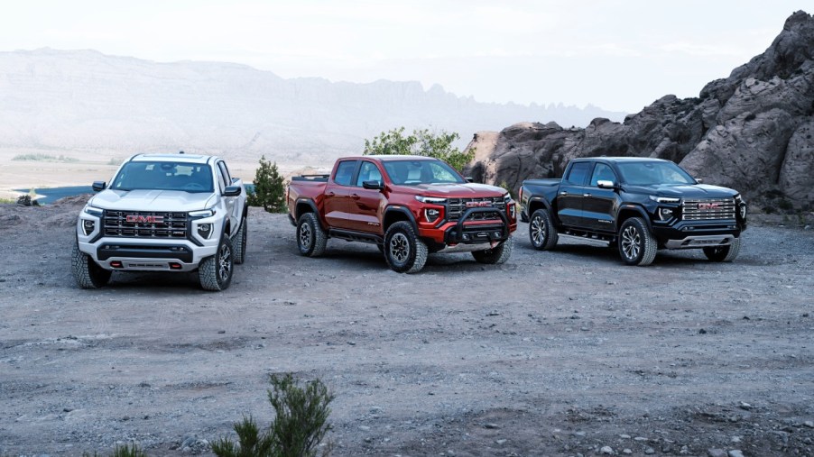 three versions of the 2023 GMC Canyon parked on a dirt area.