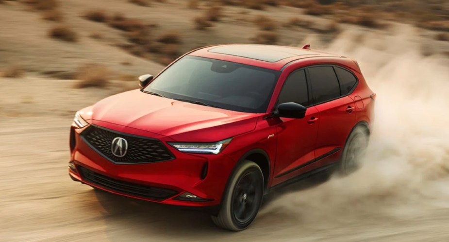 A red 2023 Acura MDX mid-size SUV drives off-road.