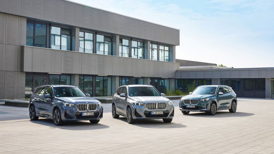 New BMW iX1 and BMW X1 SUV models parked on a plaza of stone tiles