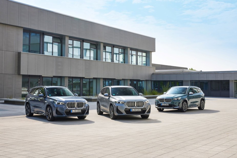 New BMW iX1 and BMW X1 SUV models parked on a plaza of stone tiles