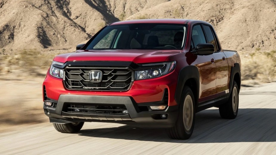 Front angle view of red 2023 Honda Ridgeline midsize pickup truck, comparing to 2023 Toyota Tacoma