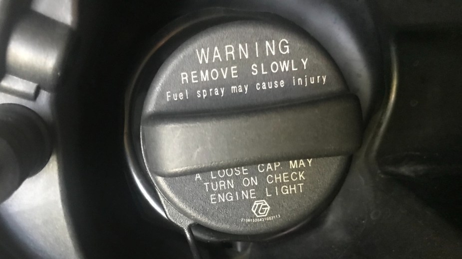 ​​Gas cap on fuel door of SUV, highlighting how tightening it can turn off check engine light in car