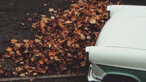 Green classic car on a leaf pile, highlighting how parking on leaves can make a car catch on fire
