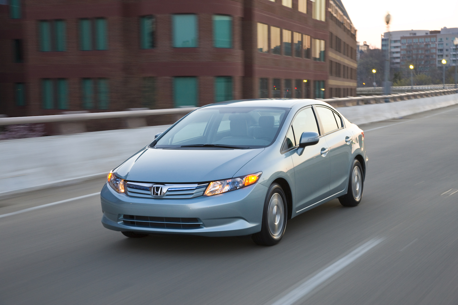 A silver Honda Civic Hybrid driving down a city street, the Honda Civic Hybrid is a fuel-efficient used hybrid sedan