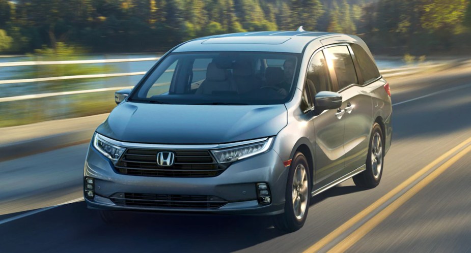 A gray 2023 Honda Odyssey minivan is driving on the road. 
