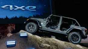 A grey Jeep Wrangler 4xe parked indoors on a fake rock.