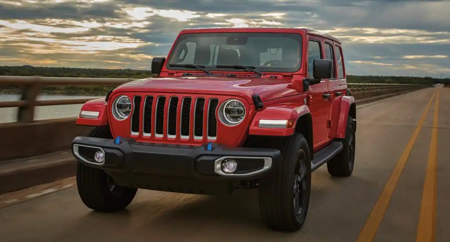 A red Jeep Wrangler is driving on the road. 