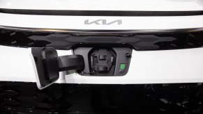 A white Kia Niro hybrid SUV front with charging port open.