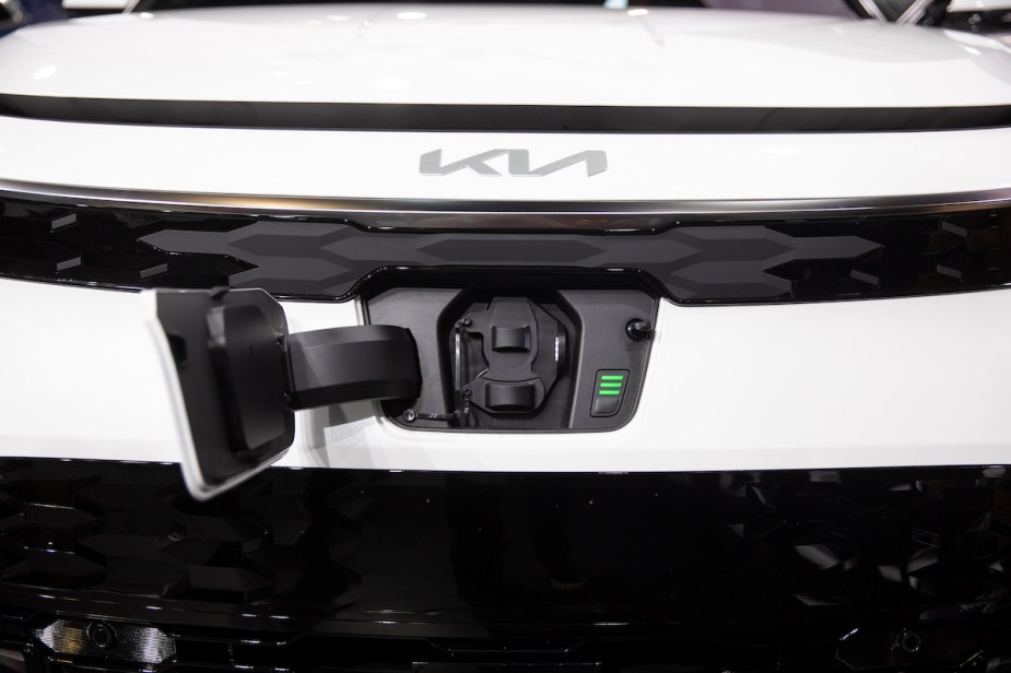A white Kia Niro hybrid SUV front with charging port open. 