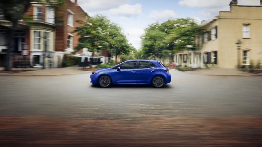 A blue 2023 Toyota Corolla Hatch Hybrid is shown in full left side view with a wide foreground.