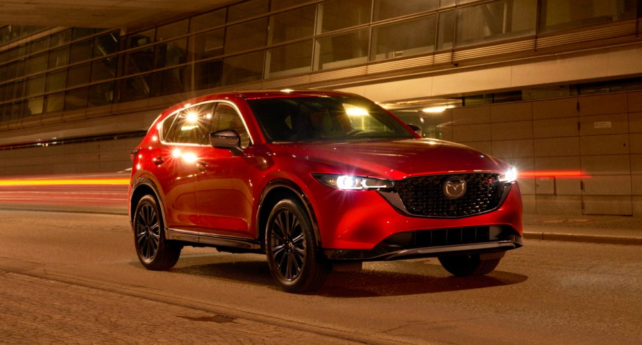 A red 2023 Mazda CX-5 small SUV is driving on the road. 